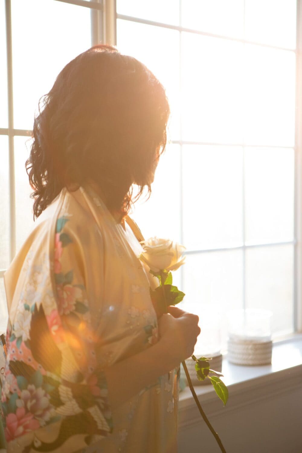 Beautiful woman with a Rose with sunlight coming through the window