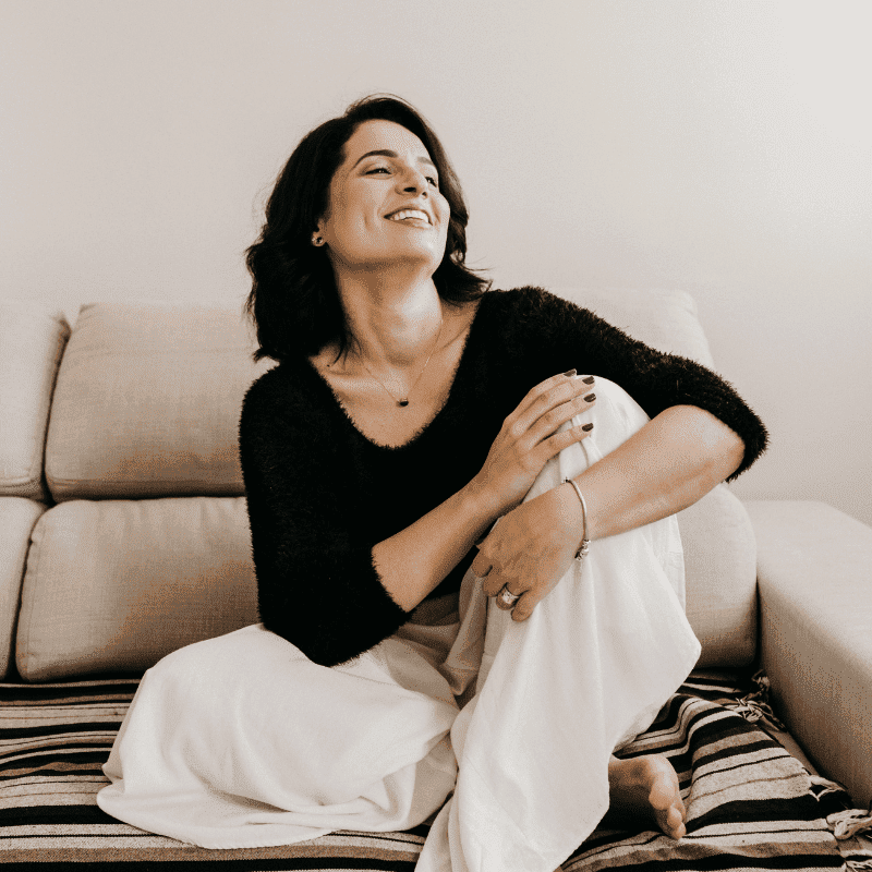 Happy Woman Sitting On Sofa With Ring On Finger Posing For Picture